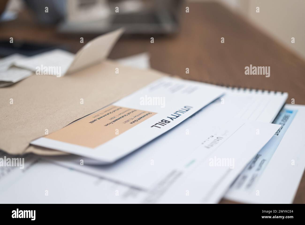 Utility bill statements, displaying due amount, alongside a phone calculator, set on a wooden table  Stock Photo