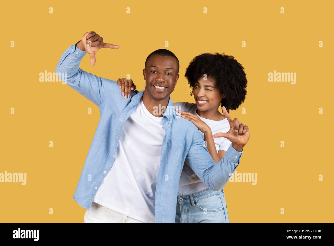 Happy couple posing with thumb gestures on yellow Stock Photo