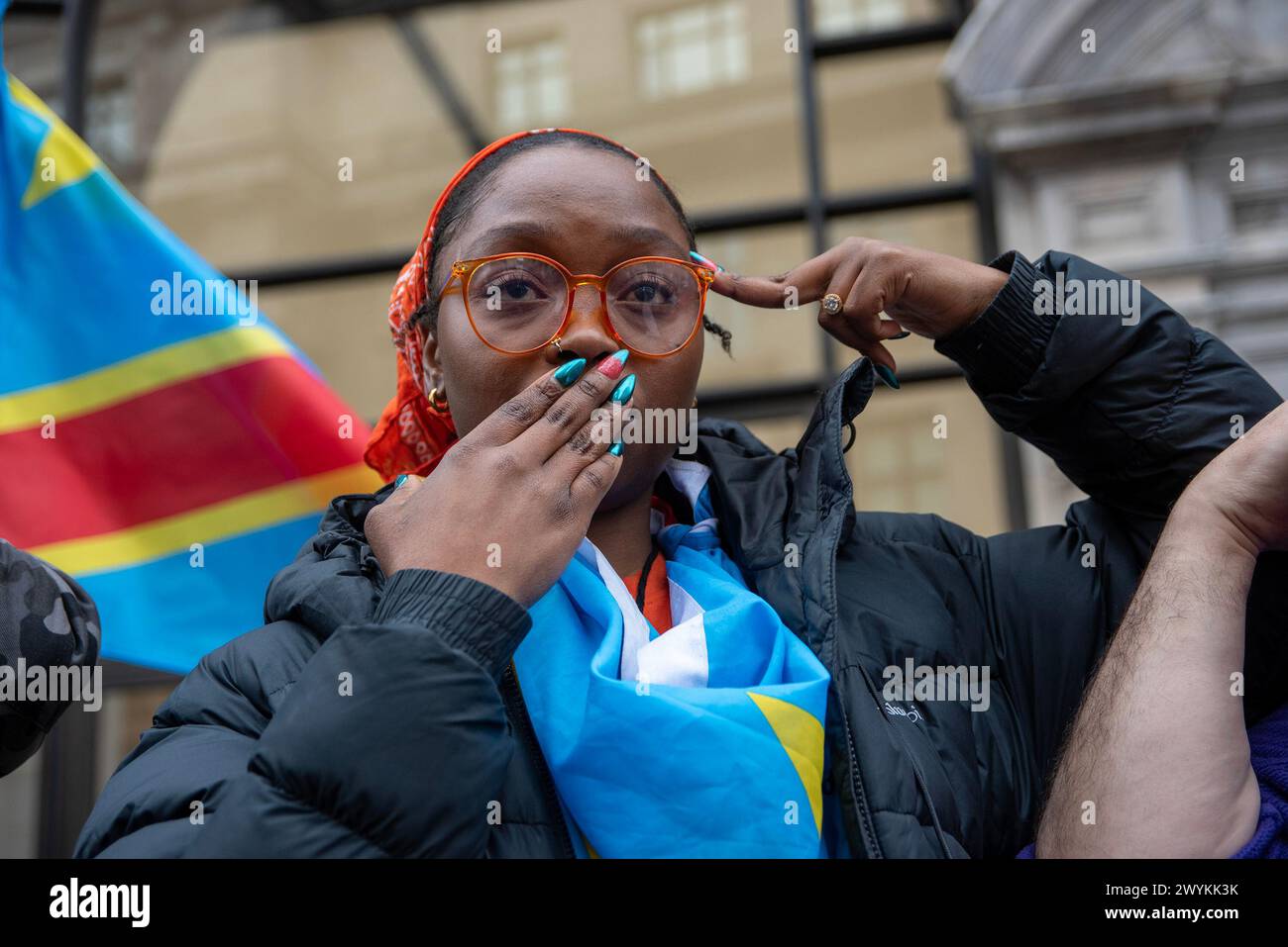 London, UK. 6th Apr, 2024. A protester holds her palm front of her mouth and put her fingers to the side of her forehead during the protest in London. Congolese diaspora and their allies protested front of the London HQ of Apple against the violence and the mineral exploitation in Eastern part of the Democratic Republic of Congo (DRC), where the fights is going on between the Congolese forces and the Rwanda backed M23 rebel group. The conflict created a growing refugee crisis, human right abuses and cheap labor for mining. All minerals like Coltan, Cobalt, etc. which are used by co Stock Photo