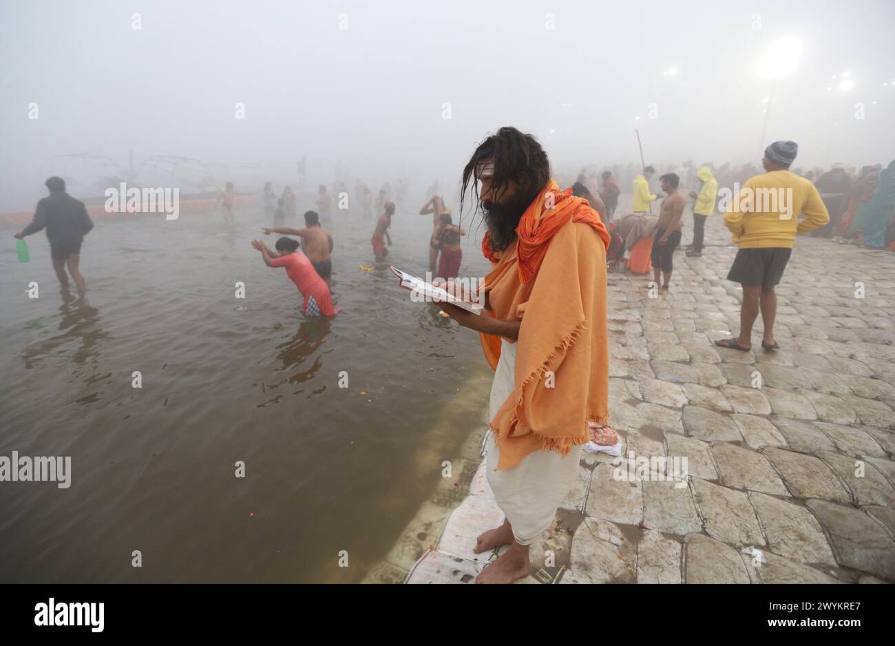 An Indian devotee reads religious book after taking holy dip in river Ganges on the occasion of Makar Sankranti during Magh Mela in Prayagraj, India. Stock Photo