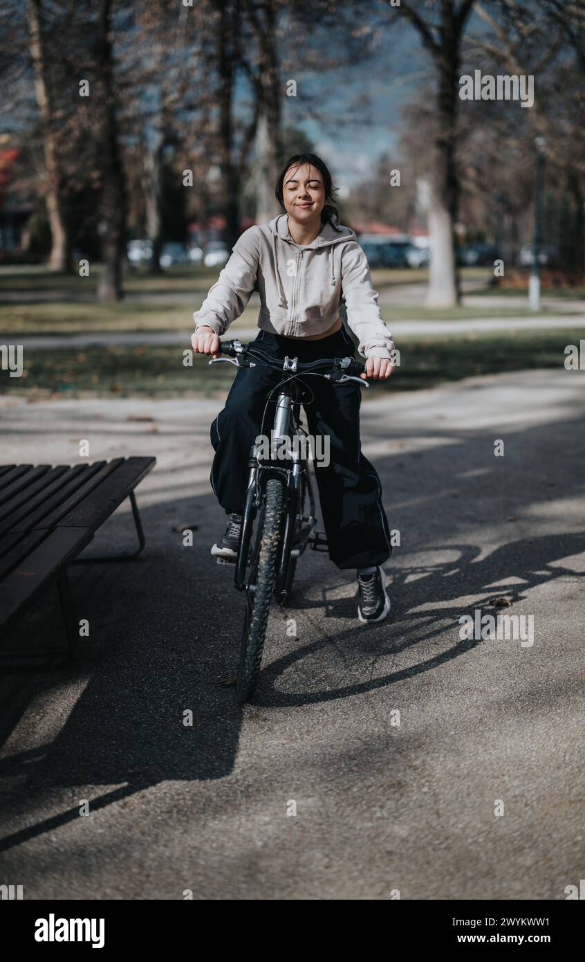 Young woman enjoying a leisurely bike ride in a park setting Stock ...