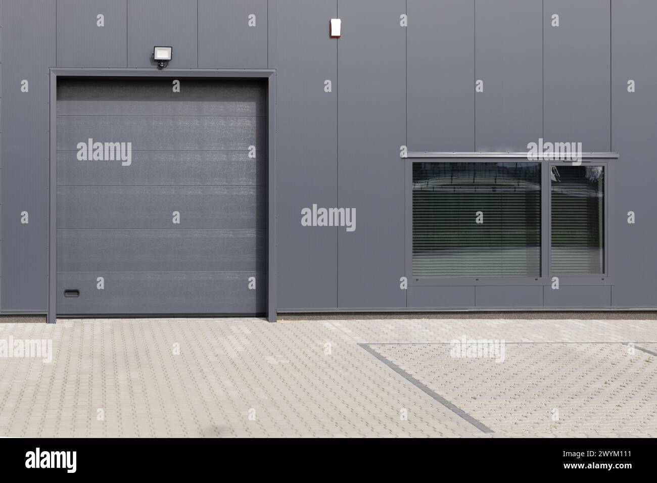 Gray industrial wall with roller shutter door and window. Modern Industrial Building Facade Stock Photo