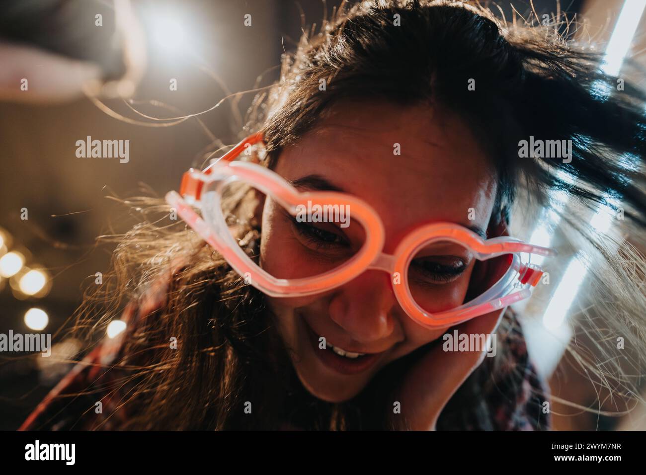 Joyful young woman with funky glasses laughing at a cozy home gathering Stock Photo