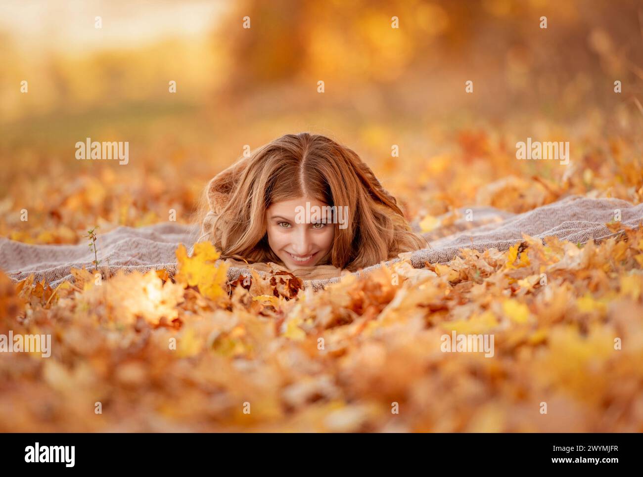 Cute teenage girl sitting in yellow leaves Stock Photo - Alamy