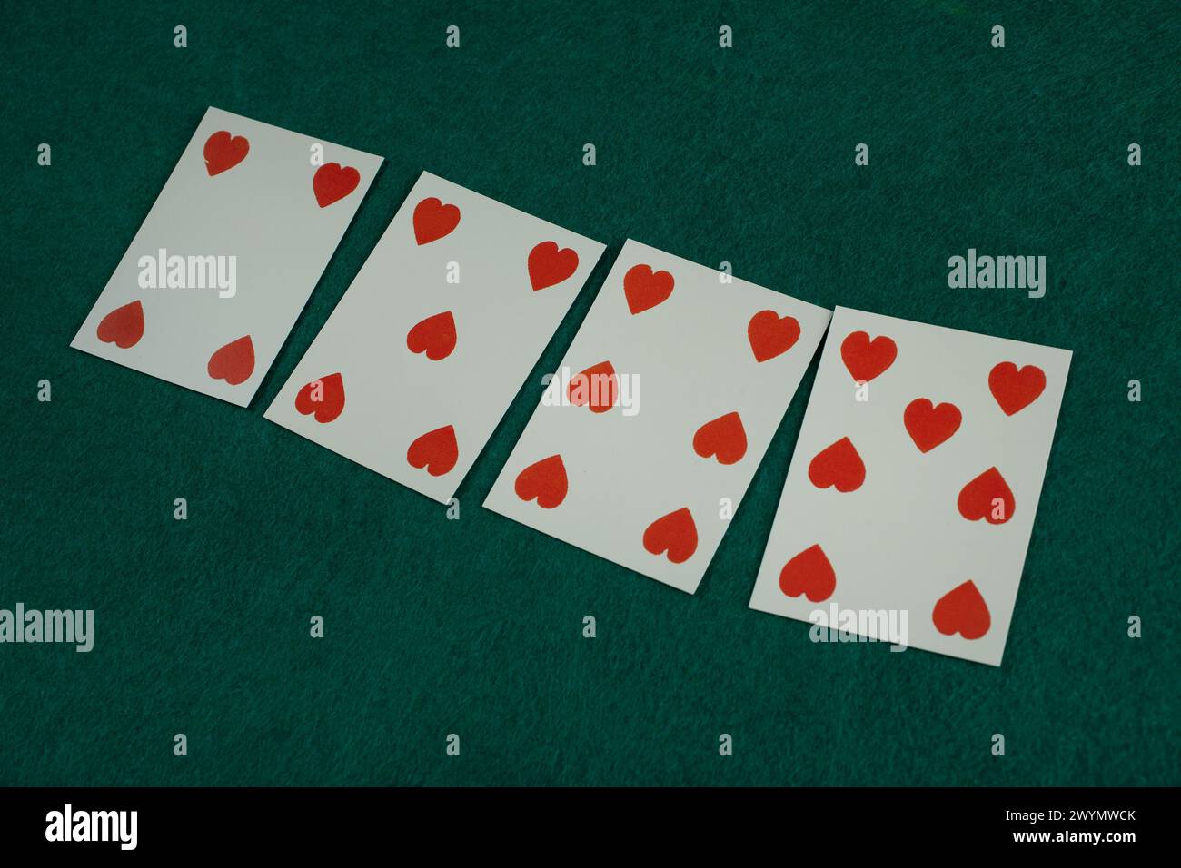 Old west era playing card on on green gambling table. 4, 5, 6, 7 of hearts. Stock Photo