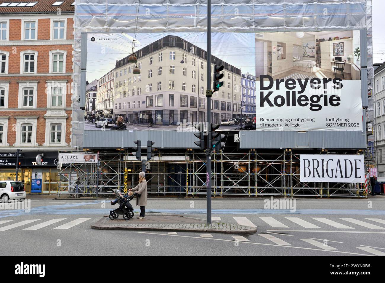 A womanwith a stroller pauses beneath an advertsing poster showing a rendition of how the street will look after a renovation in Frederiksberg, Copenh Stock Photo