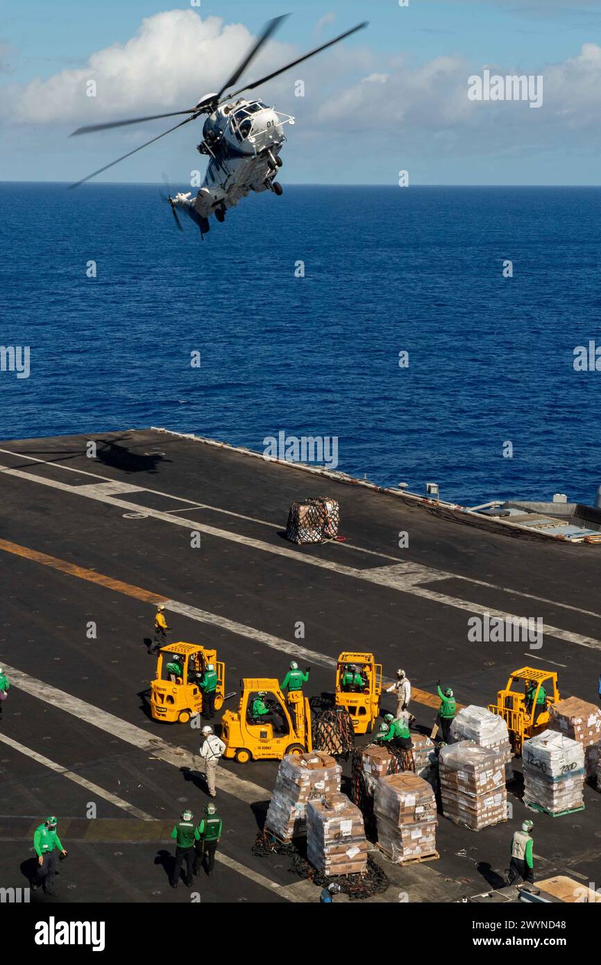 PHILIPPINE SEA (April 5, 2024) An AS-332 Super Puma, assigned to the Lewis and Clark-class dry cargo ship USNS Wally Schirra (T-AKE 8), drops off supplies during a vertical replenishment with the Nimitz-class aircraft carrier USS Theodore Roosevelt (CVN 71), April 5, 2024. Theodore Roosevelt, flagship of Carrier Strike Group Nine, is underway conducting routine operations in the U.S. 7th Fleet area of operations. U.S. 7th Fleet is the U.S. Navy’s largest forward-deployed numbered fleet, and routinely interacts and operates with allies and partners in preserving a free and open Indo-Pacific reg Stock Photo