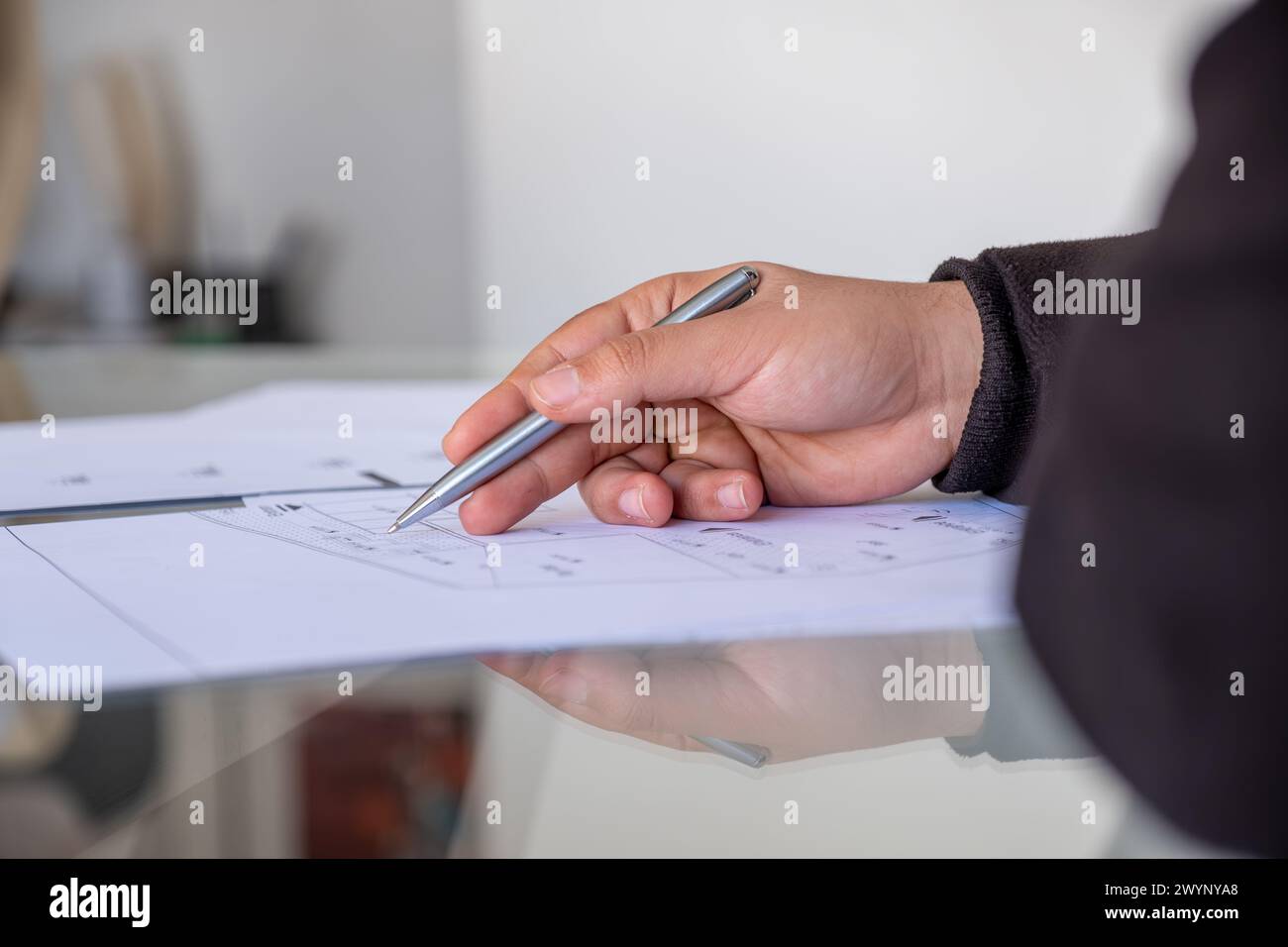 male holding pen while checking projects papers on glass table with reflections Stock Photo