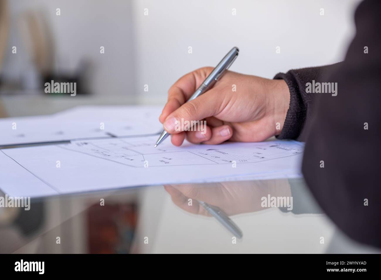 male holding pen while checking projects papers on glass table with reflections Stock Photo