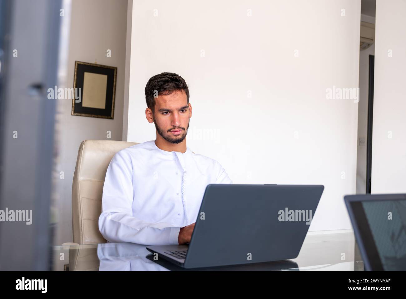 confident arabic male working on his laptop with modern background ...