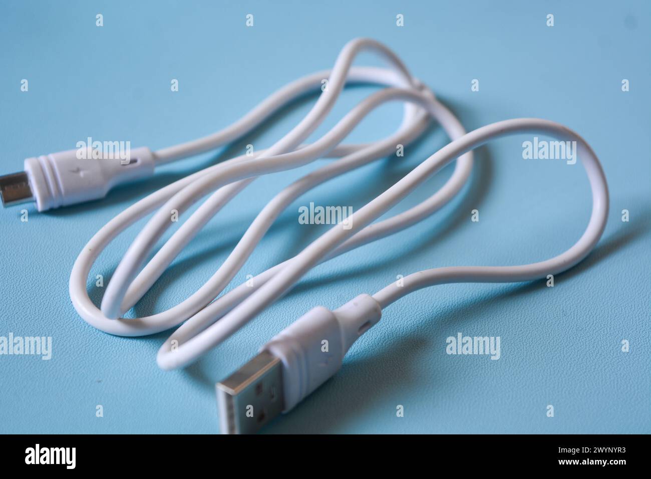 White folded usb and micro usb cable on blue background. Stock Photo