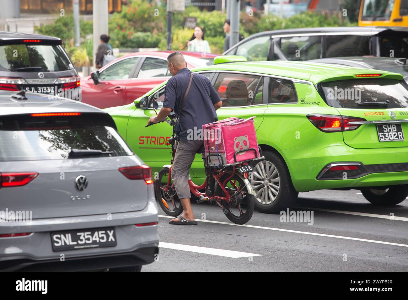 A food delivery rider on his electric bicycle stops in the middle of ...