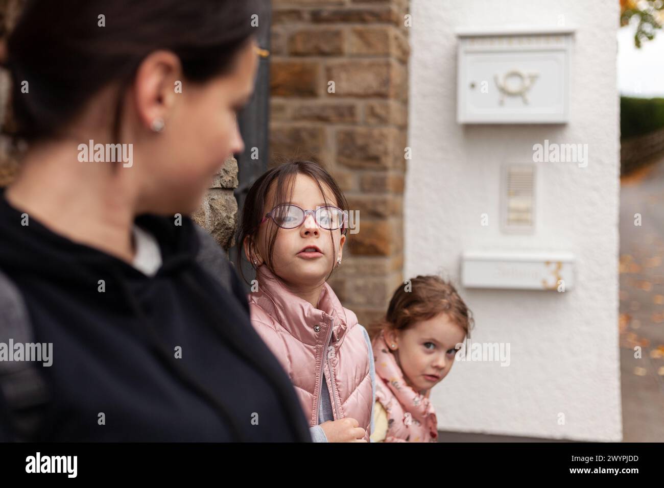 Mother and her two daughters looking at each other in the street. Stock Photo