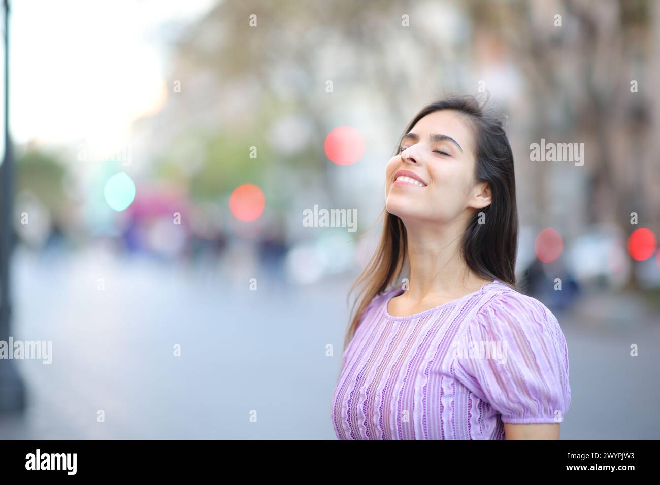 Happy woman breathing fresh air in the middle of the street Stock Photo