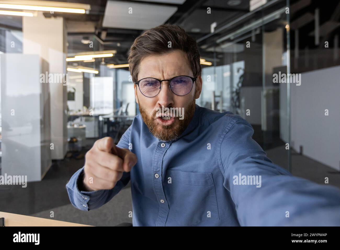 An irate male office worker gesticulates while shouting on a phone call