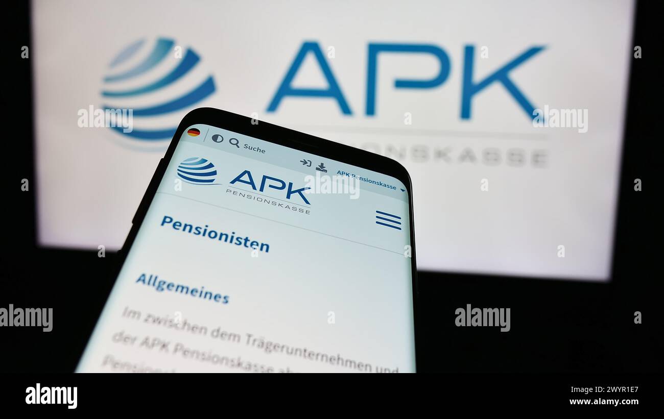 Mobile phone with website of pension scheme institution APK Pensionskasse AG in front of logo. Focus on top-left of phone display. Stock Photo