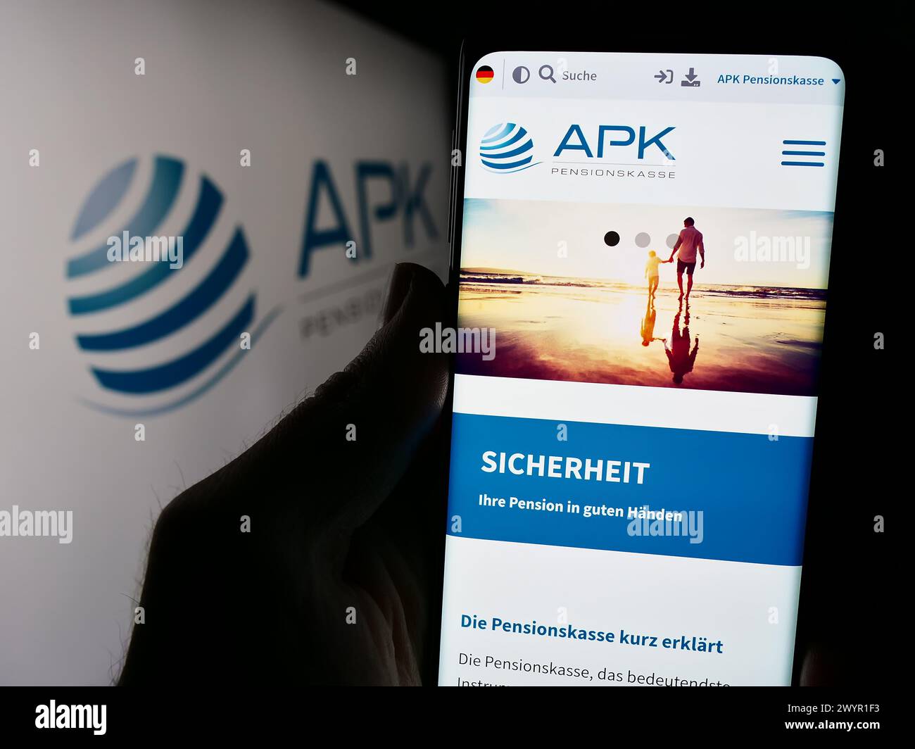 Person holding cellphone with webpage of pension scheme institution APK Pensionskasse AG in front of logo. Focus on center of phone display. Stock Photo