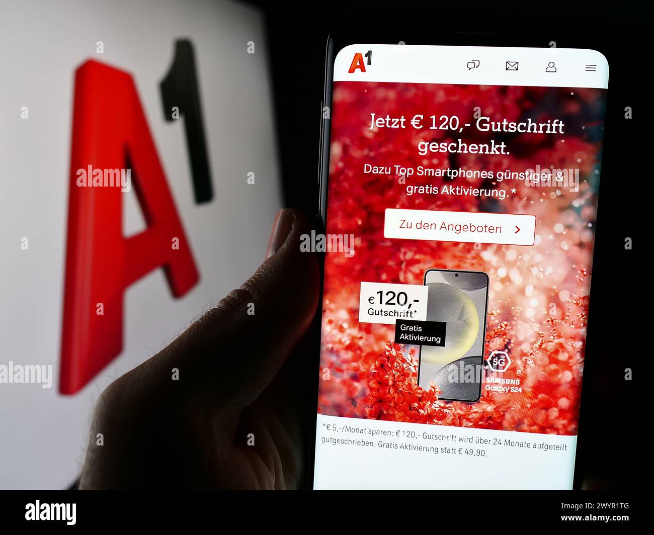 Person holding cellphone with webpage of telecommunications company Telekom Austria AG (A1) in front of logo. Focus on center of phone display. Stock Photo