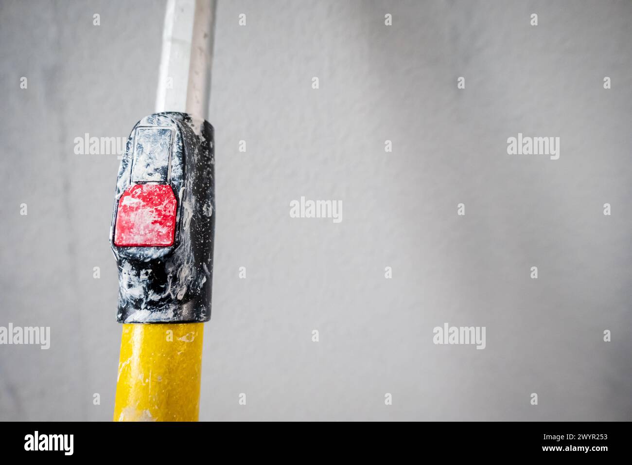 Paint roller extendable pole over painted woodchip wallpaper wall