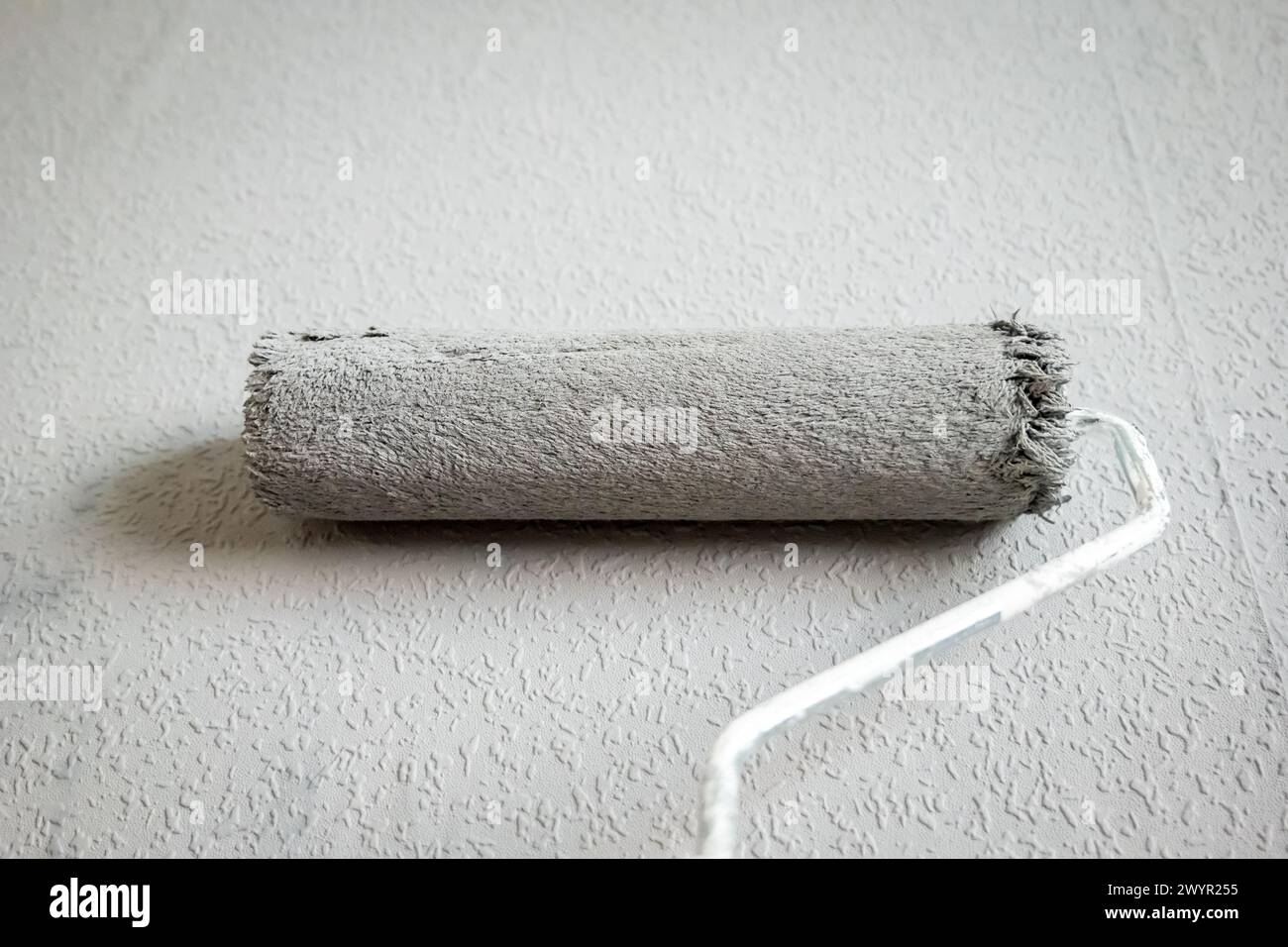 Paint roller extendable pole over painted woodchip wallpaper wall