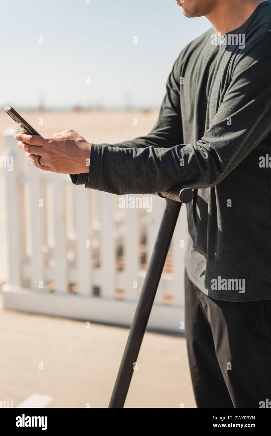 Man using smartphone while on an electric scooter at the beach Stock Photo