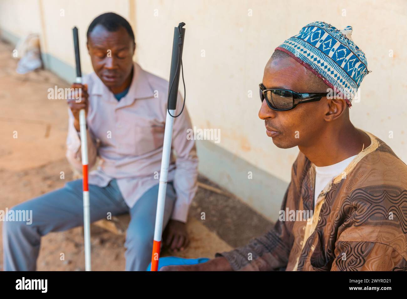 Two blind men sitting on a bench chatting, disabled people together. Stock Photo