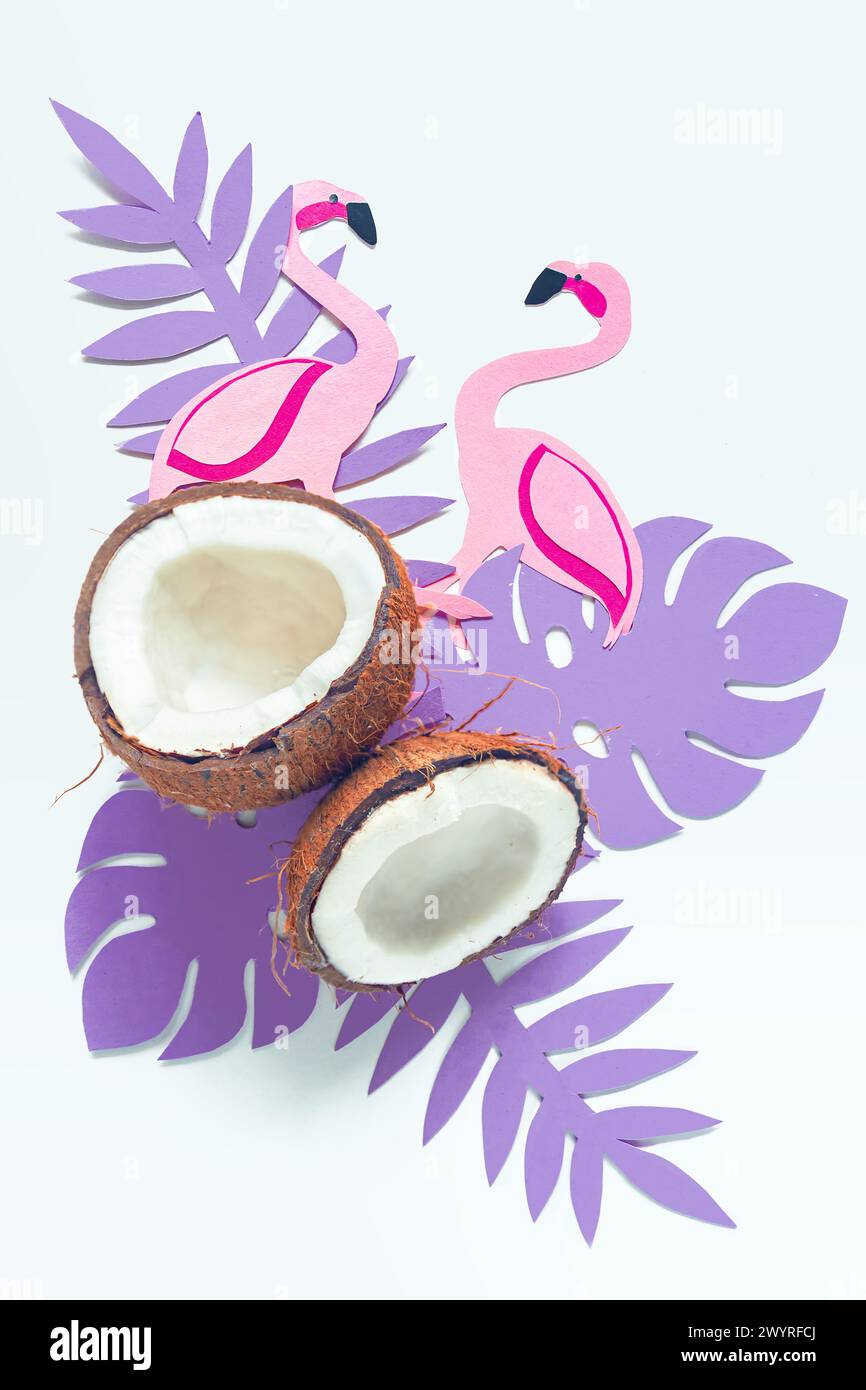 Broken coconut, paper tropical leaves and flamingos on a white background. Summer background, flat lay. Stock Photo