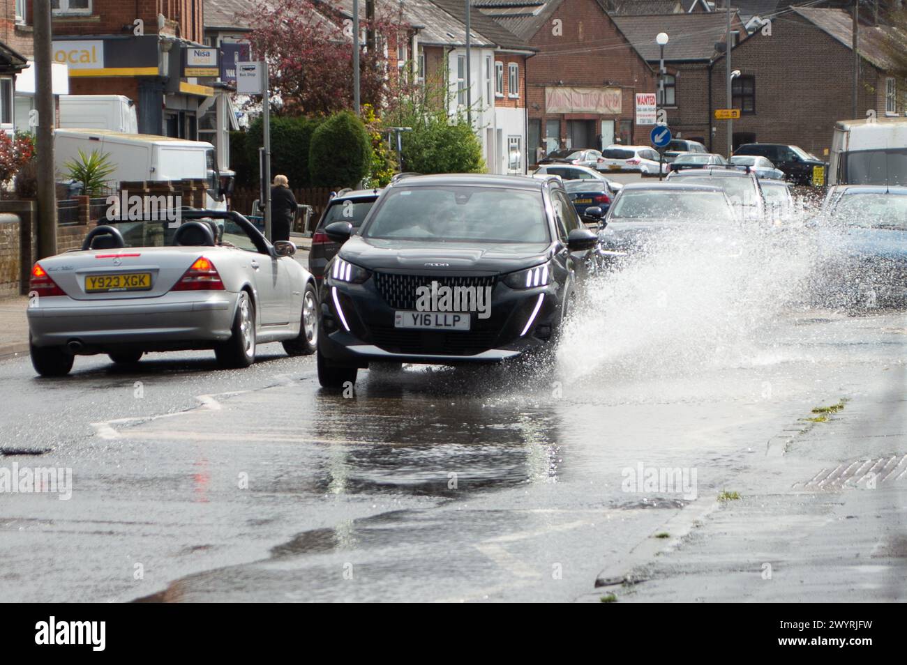 Chesham, Buckinghamshire, UK. 5th April, 2024. Water pours out of a blocked drain on a main road through Chesham, Buckinghamhire. Some cars were driving through the water at speed and splashing passers by. Credit: Maureen McLean/Alamy Stock Photo