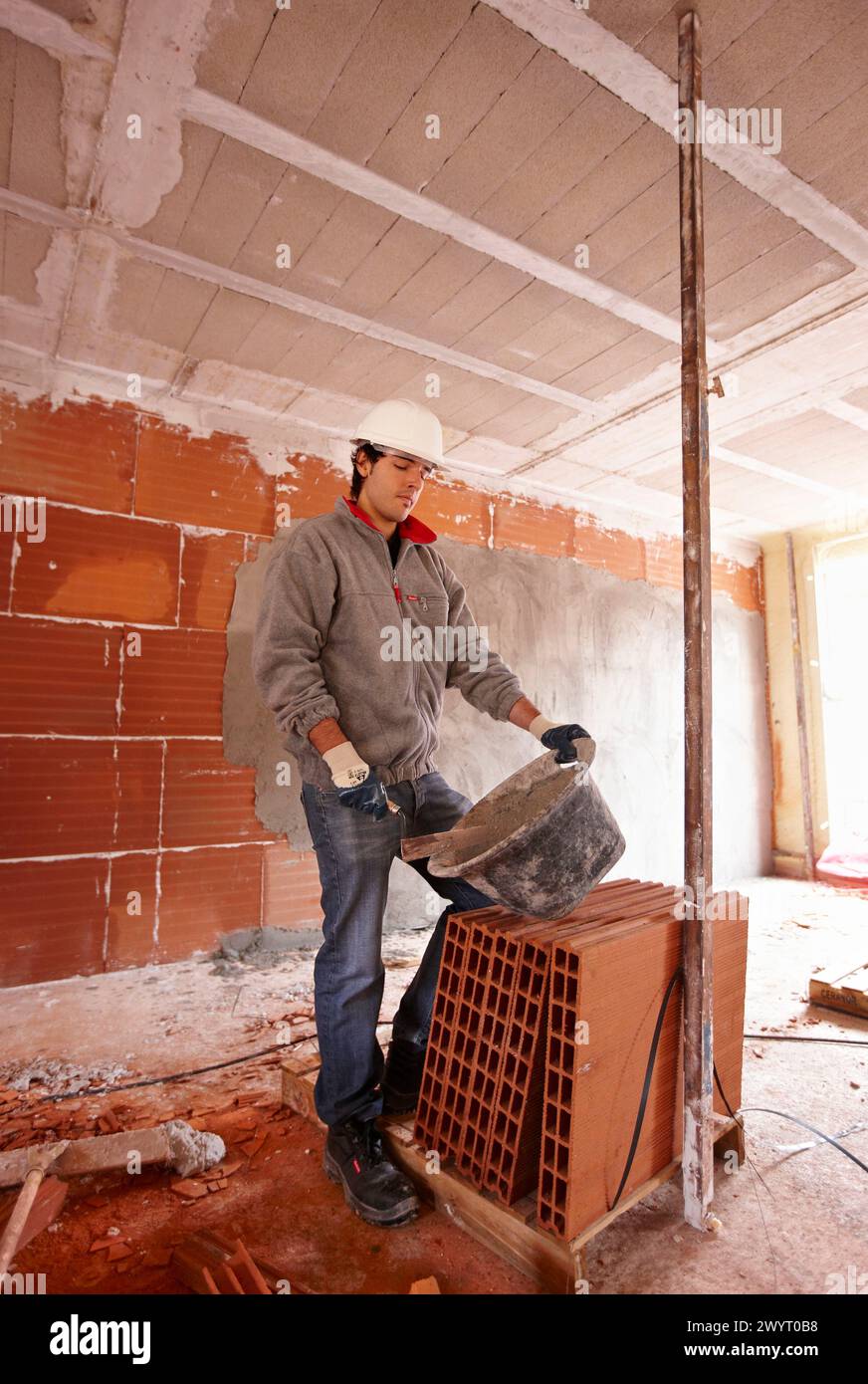 Bricklayer with trowel, bricks, new homes under construction, construction site. Stock Photo