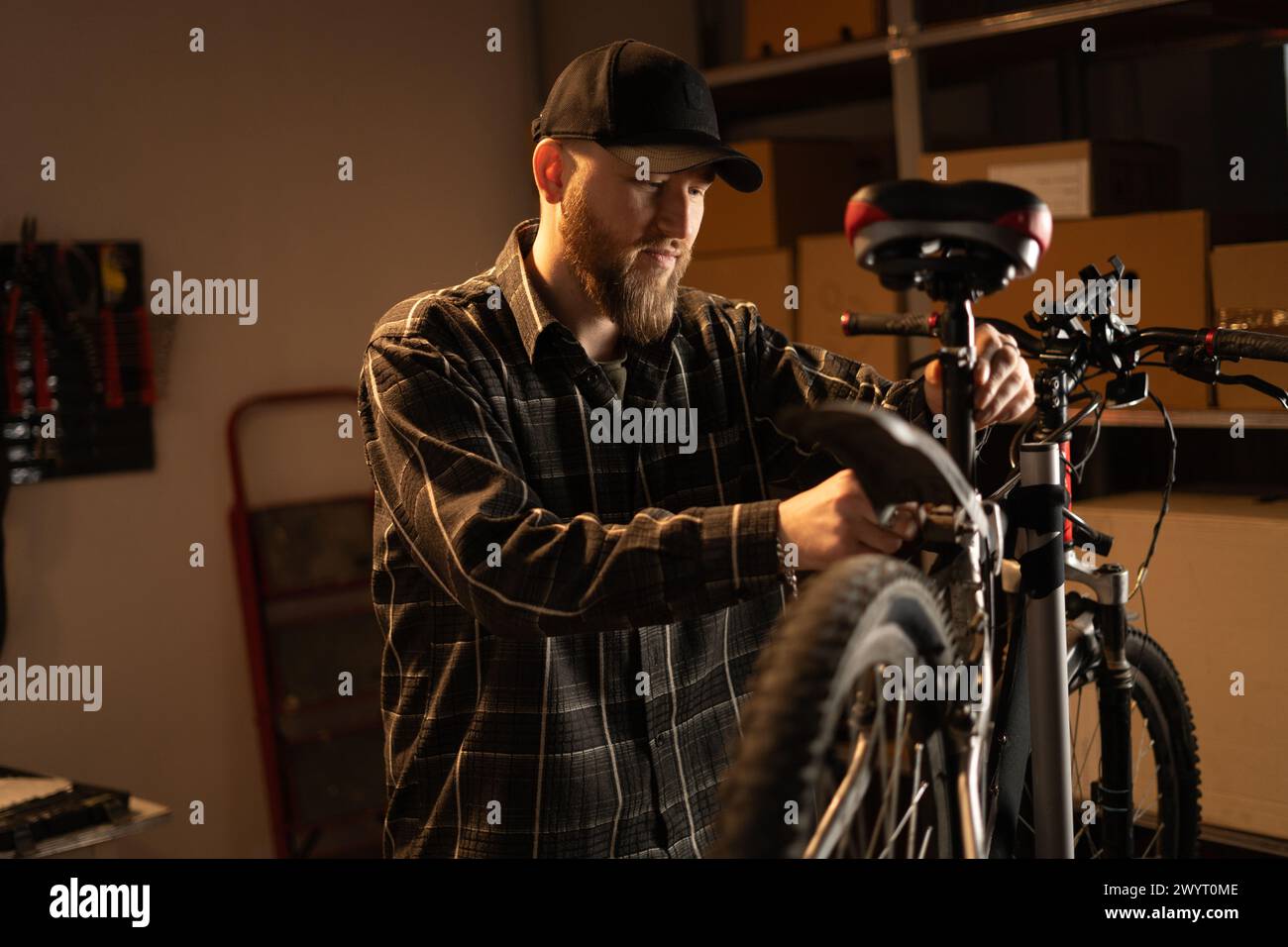 Handsome bearded mechanic repairing bicycles in a workshop or garage. Stock Photo