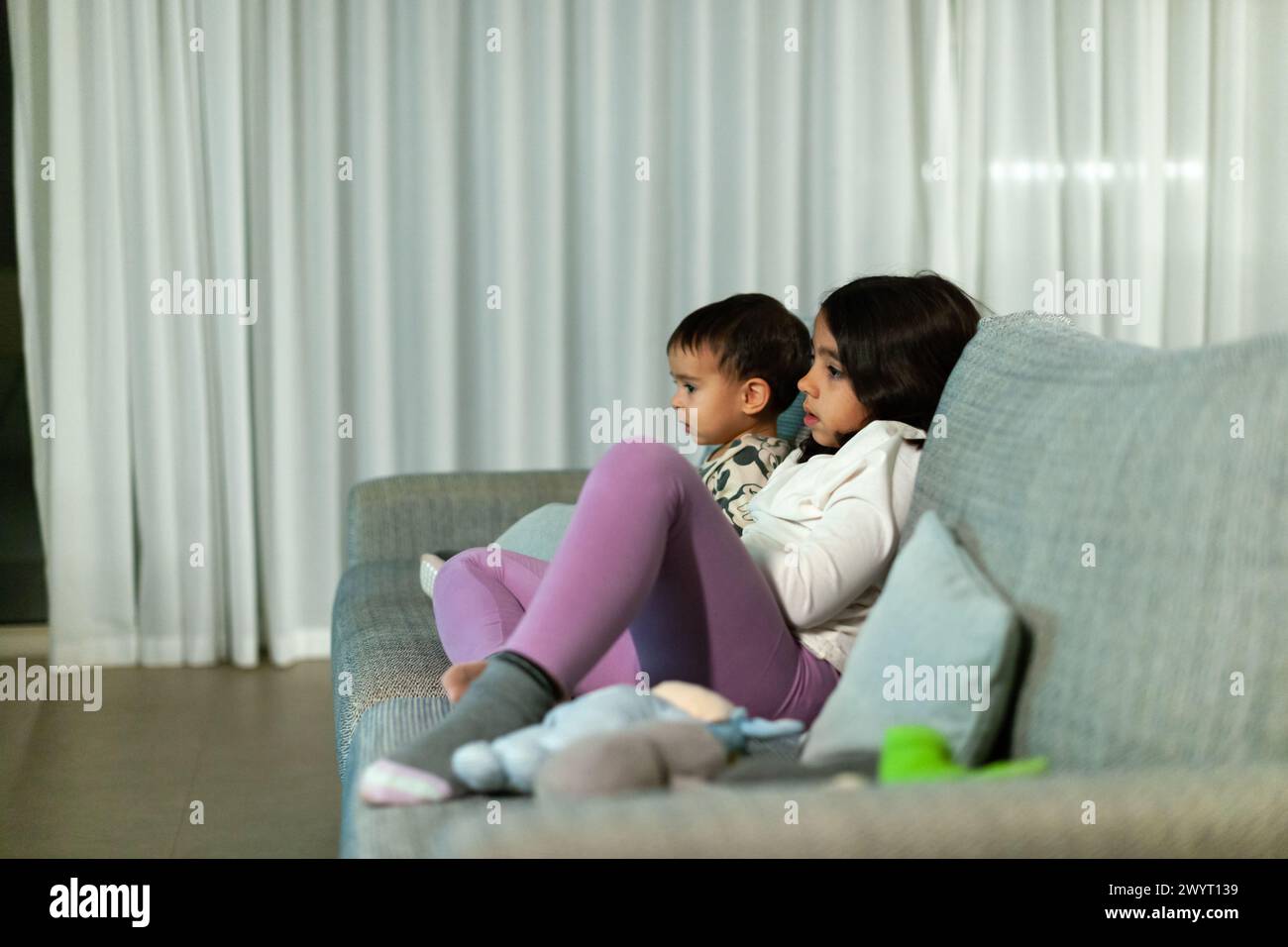 Children watching TV on the sofa at home Stock Photo