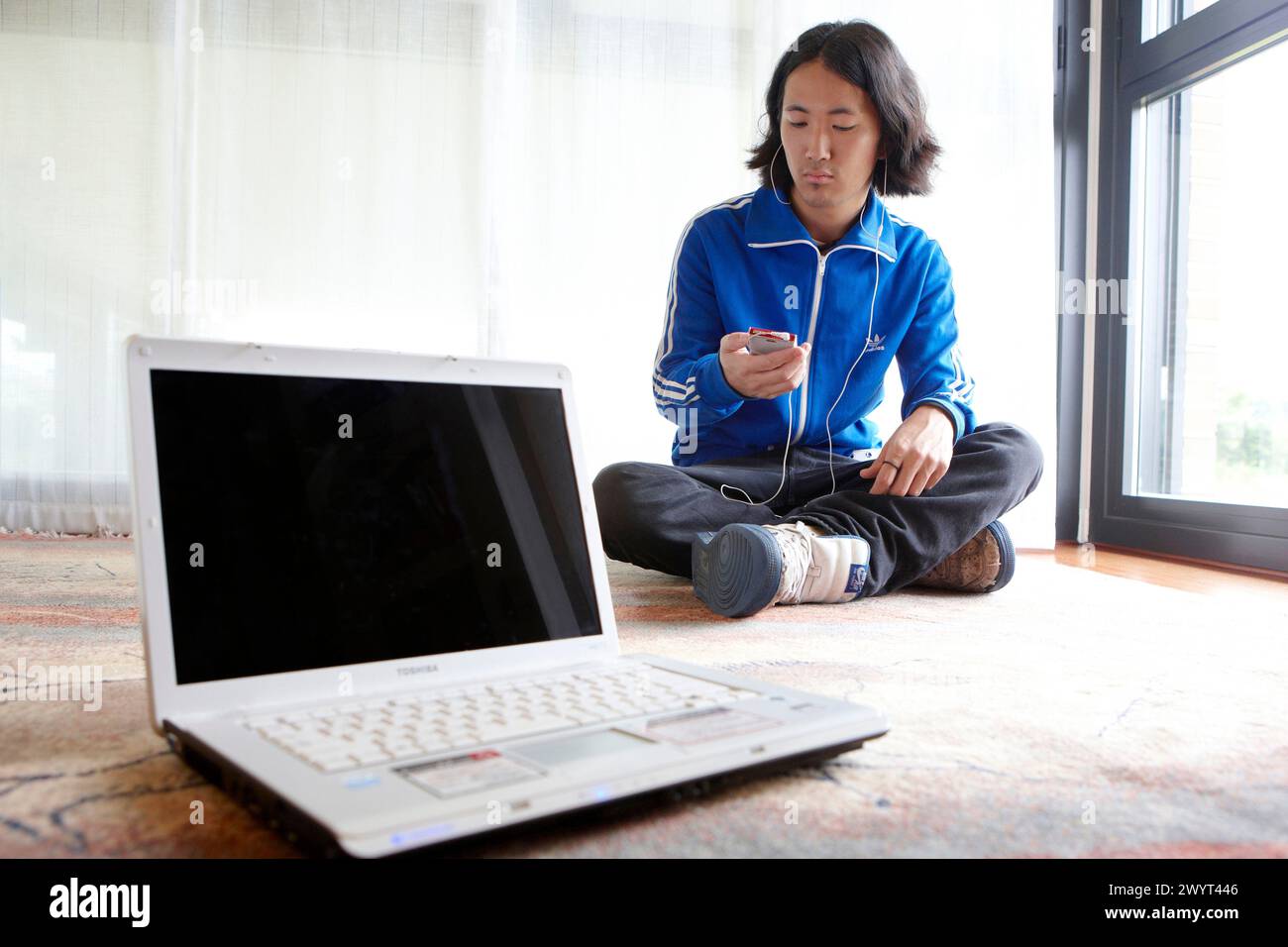 Young Japanese man with laptop computer in room. Stock Photo