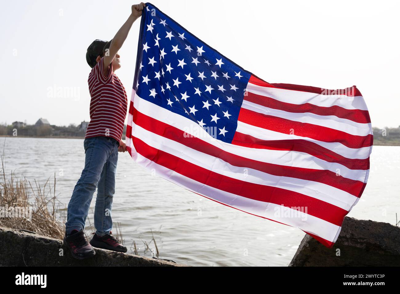 large American flag flutters in the hands of a boy. Independence Day. National symbol of freedom of the States of America. Bright future. patriotic ho Stock Photo