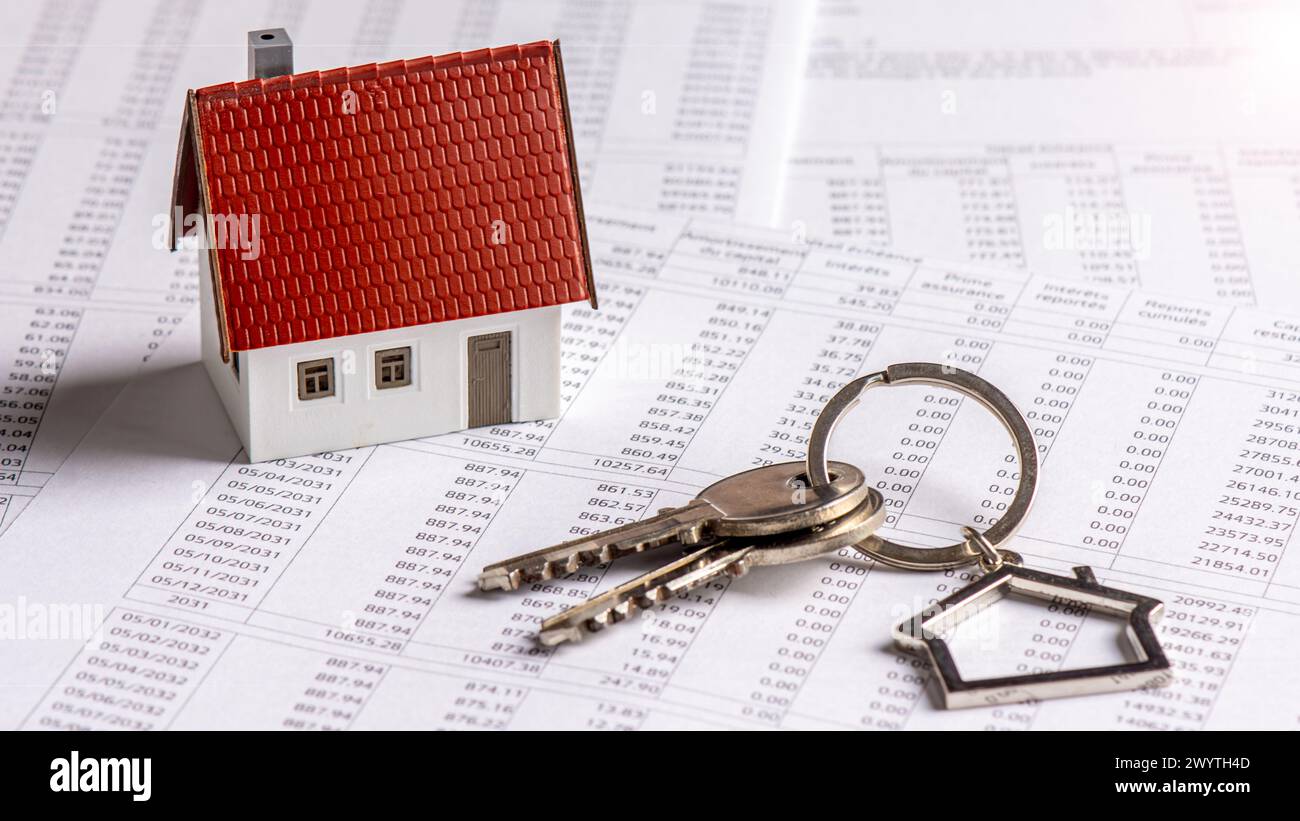 Model house with keys on a French real estate loan schedule document. Concepts of mortgage payments, credit duration and interest rates Stock Photo