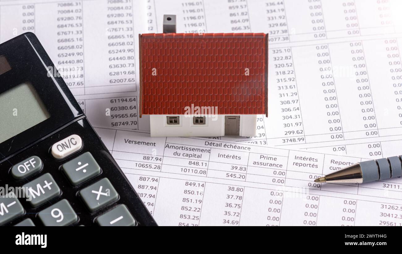 Model house with a calculator on a French real estate loan schedule document. Concepts of mortgage payments, credit duration and interest rates Stock Photo