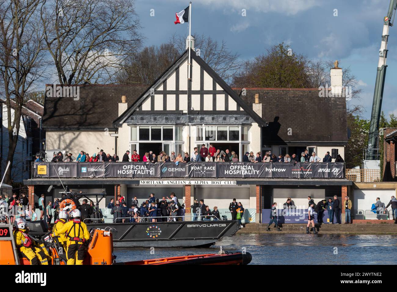 Mortlake Anglian & Alpha Boat Club at the finish of the University Boat Race event on the River Thames, London, UK. Rowers, supporters and chase boats Stock Photo
