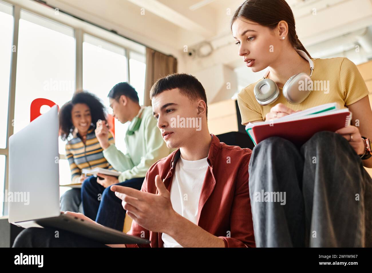 Multicultural students sit intently before a laptop, engrossed in ...
