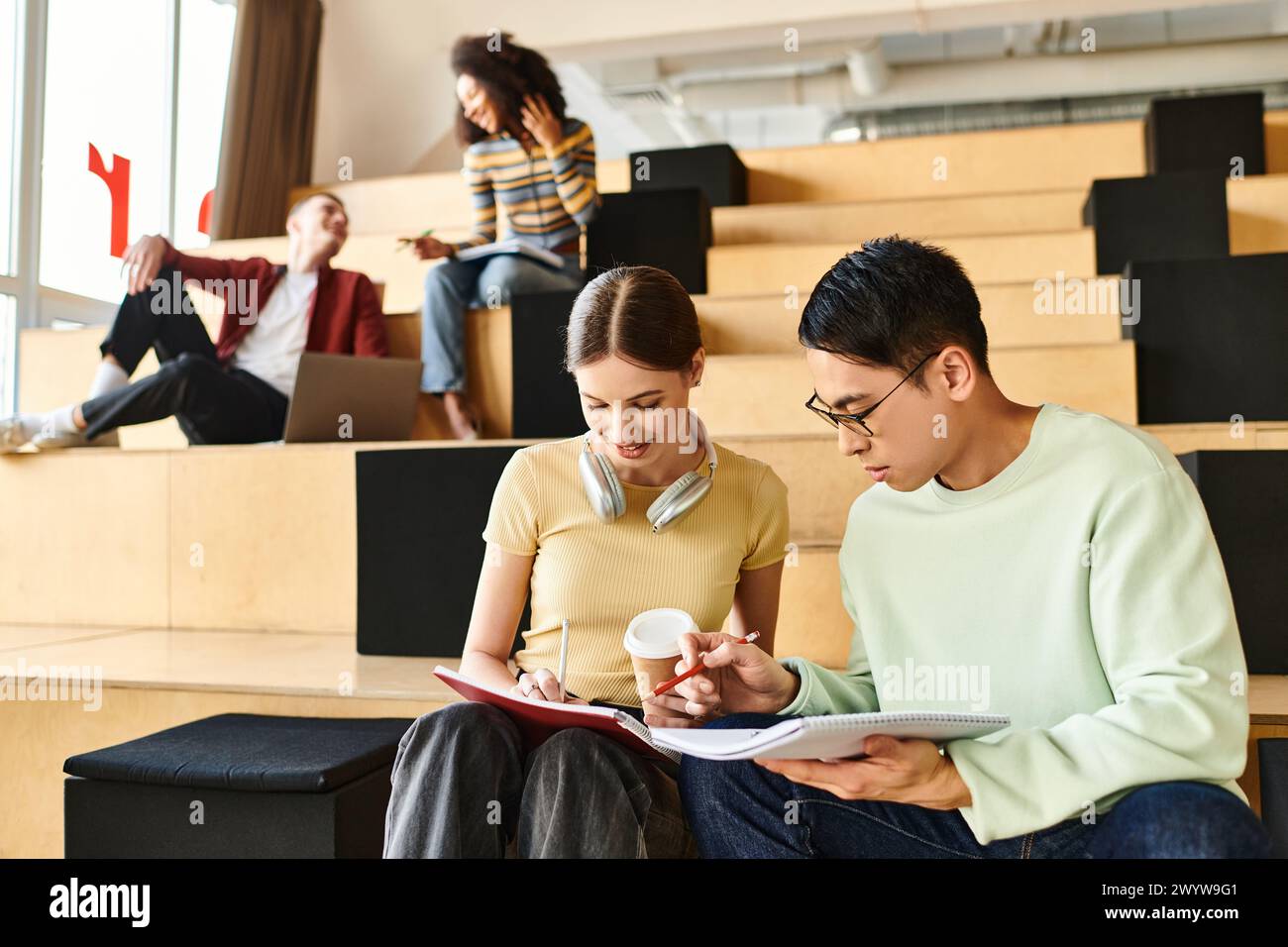 A multicultural couple peacefully sitting on stairs, engrossed in conversation in an indoor setting Stock Photo
