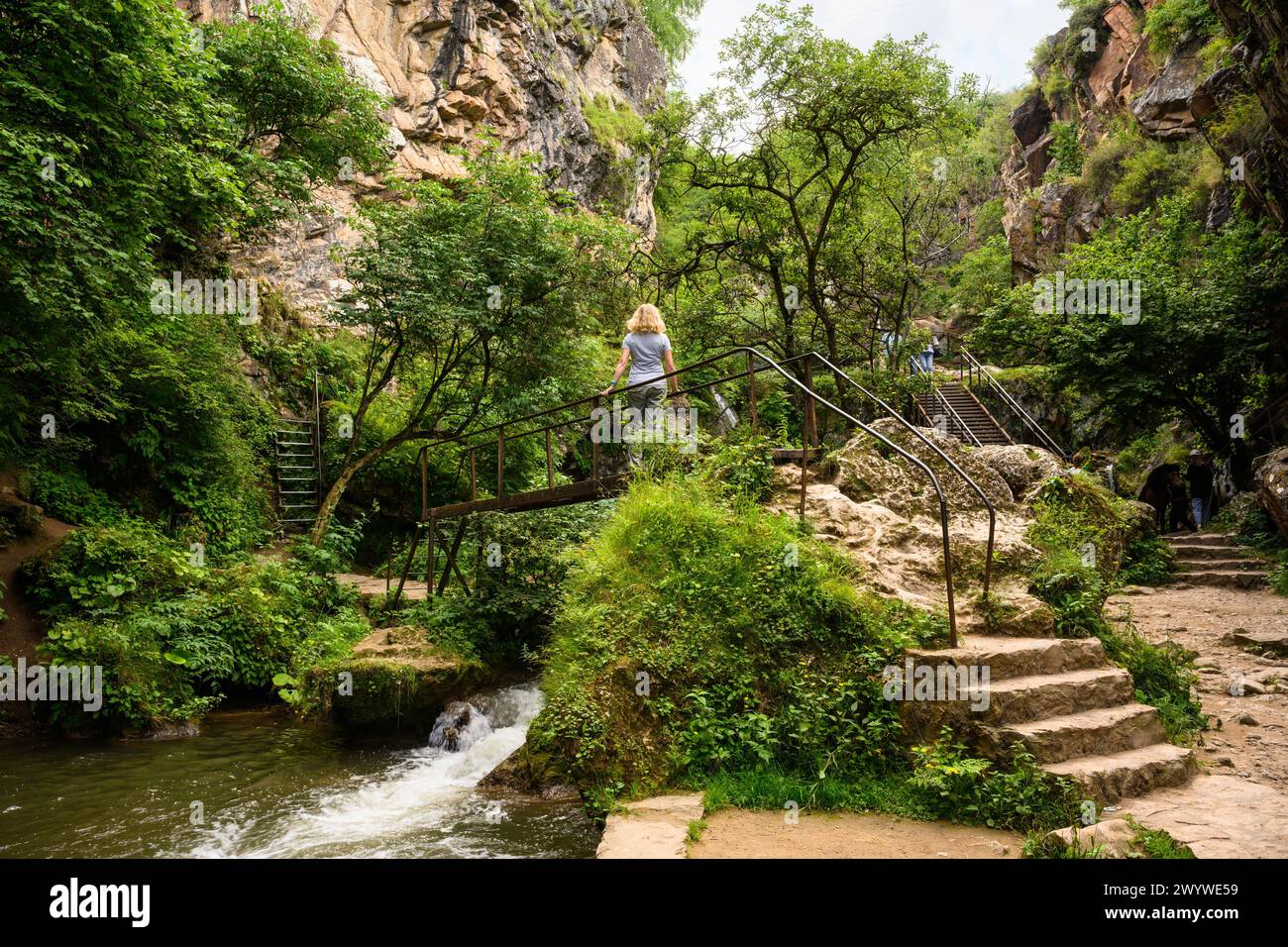 Scenic canyon at Honey Waterfalls near Kislovodsk, Russia. Mountain landscape and hiker on small bridge in summer. Concept of nature, travel, tourism, Stock Photo