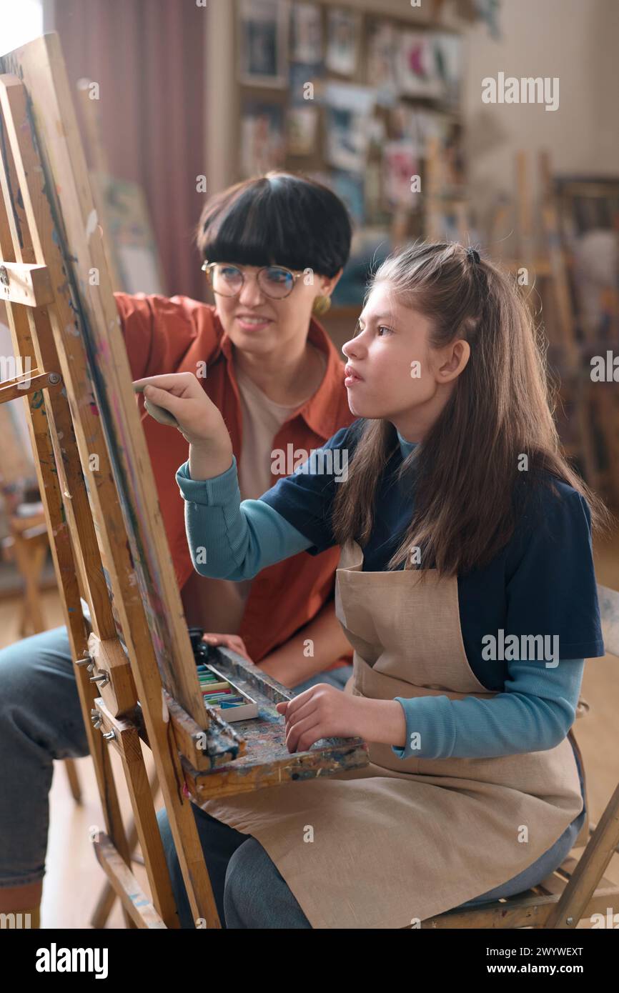 Vertical portrait of young girl with disability enjoying art class and ...