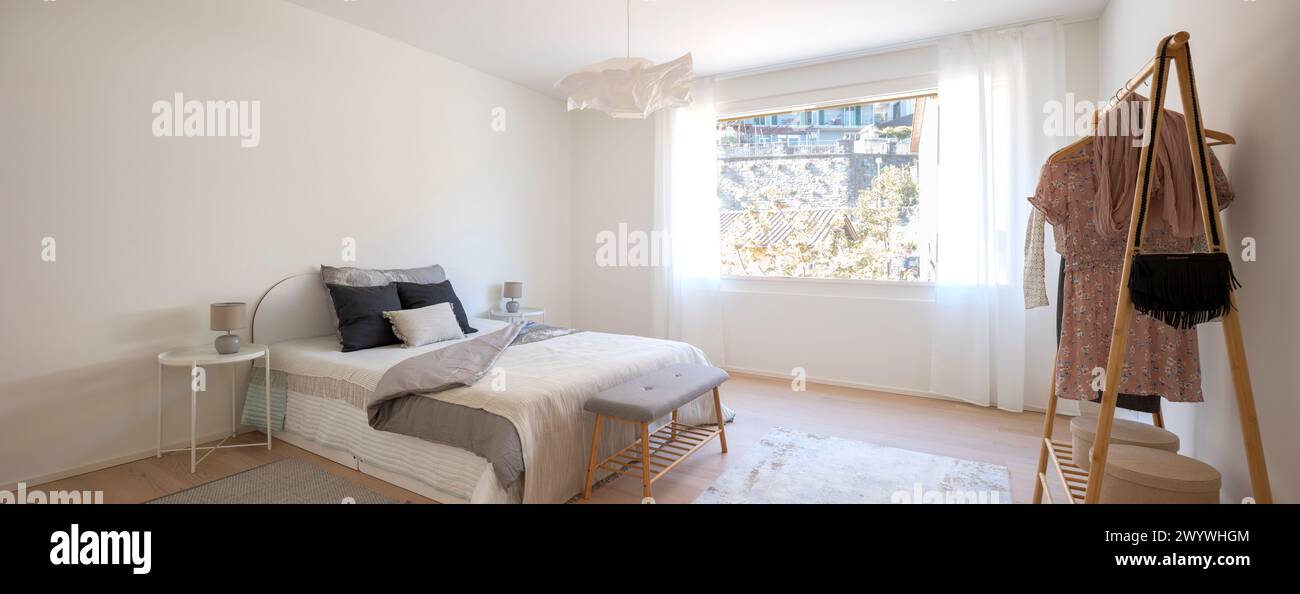 Bedroom interior with bed and large window. No people inside. These are modern rooms with white walls in the floor a carpet. Stock Photo