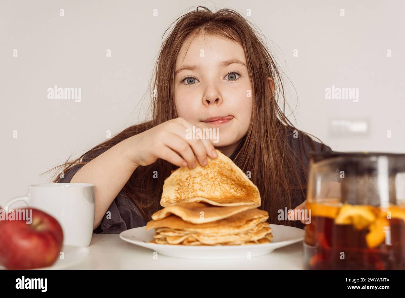 Teenage girl prepares to eat a stack of pancakes while licking her lips. Selected Focus. High quality photo Stock Photo