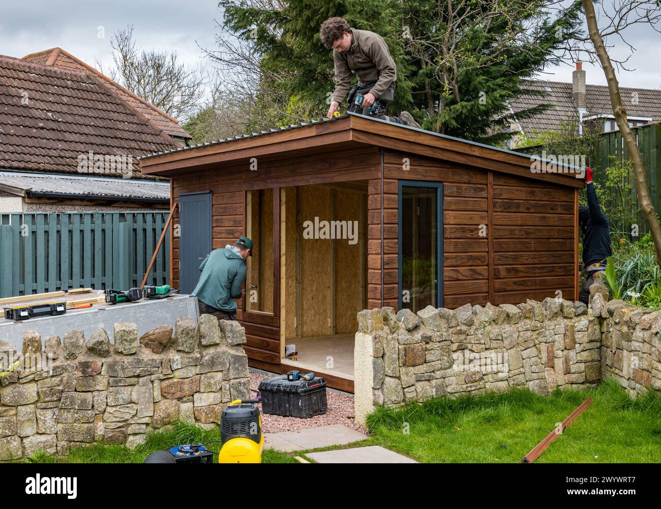 Joiners and workmen fitting a roof to construct a shed and garden room, Scotland, UK Stock Photo