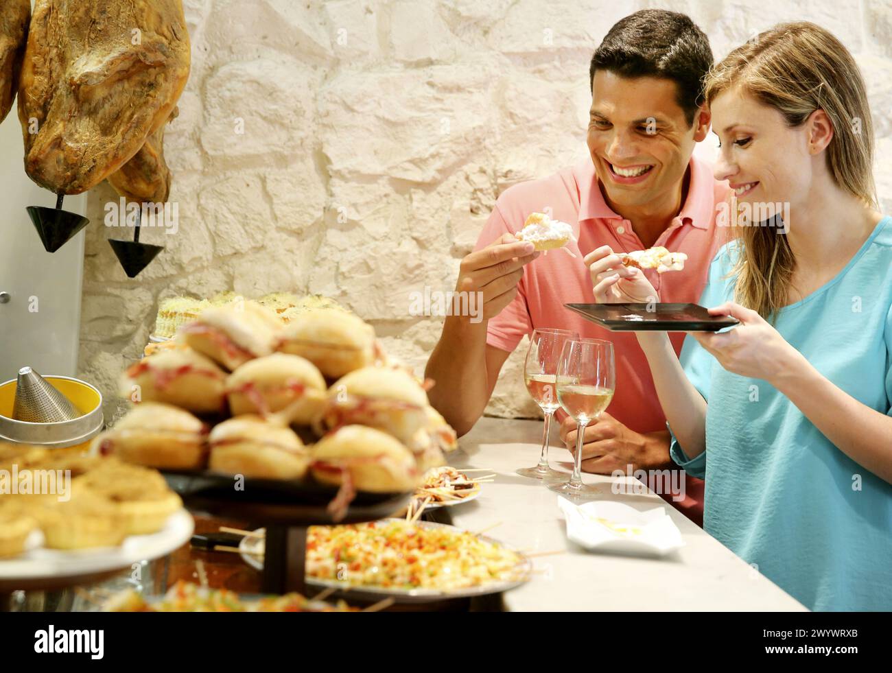 Couple drinking wine and eating tapas. Pintxos. Bar txondorra. Parte Vieja. Old town. San Sebastian. Donostia. Gipuzkoa. Basque Country. Spain. Stock Photo