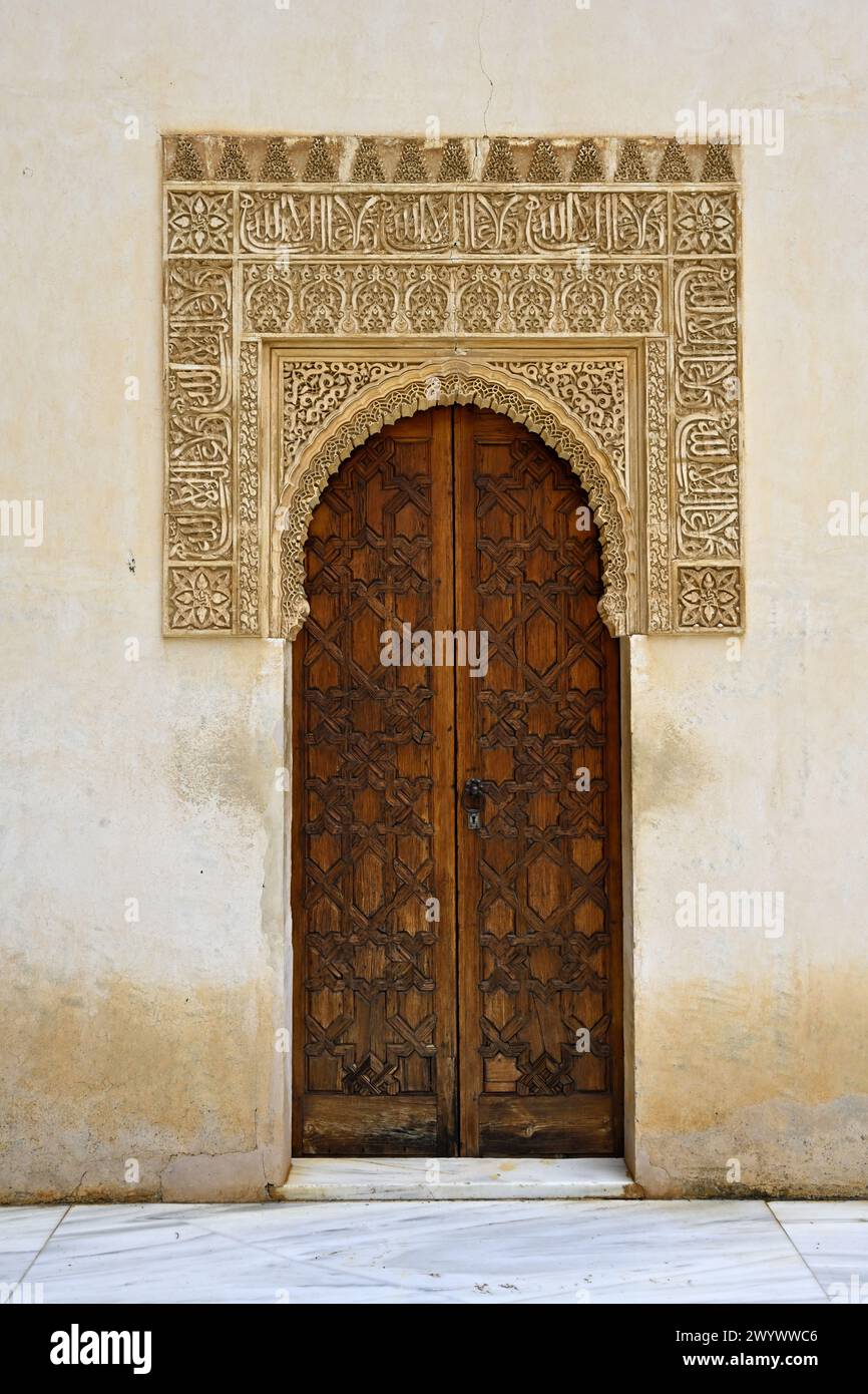 Moorish-style elaborate plasterwork and arched double wooden door inside Nasrid Palaces, Alhambra Palace, Granada, Spain Stock Photo