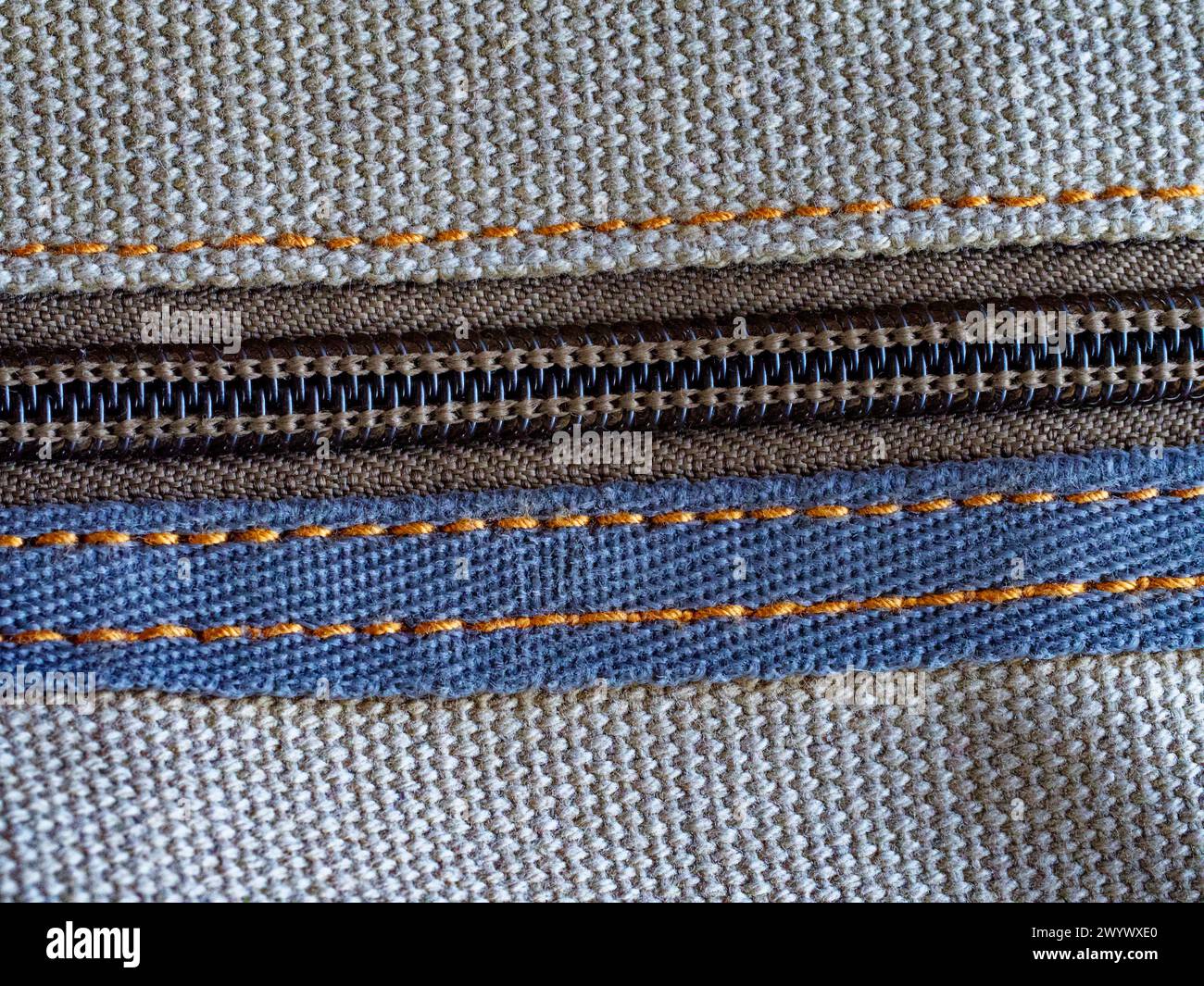 Gray fabric with a closed zipper, focusing on the intricate stitching detail. Stock Photo