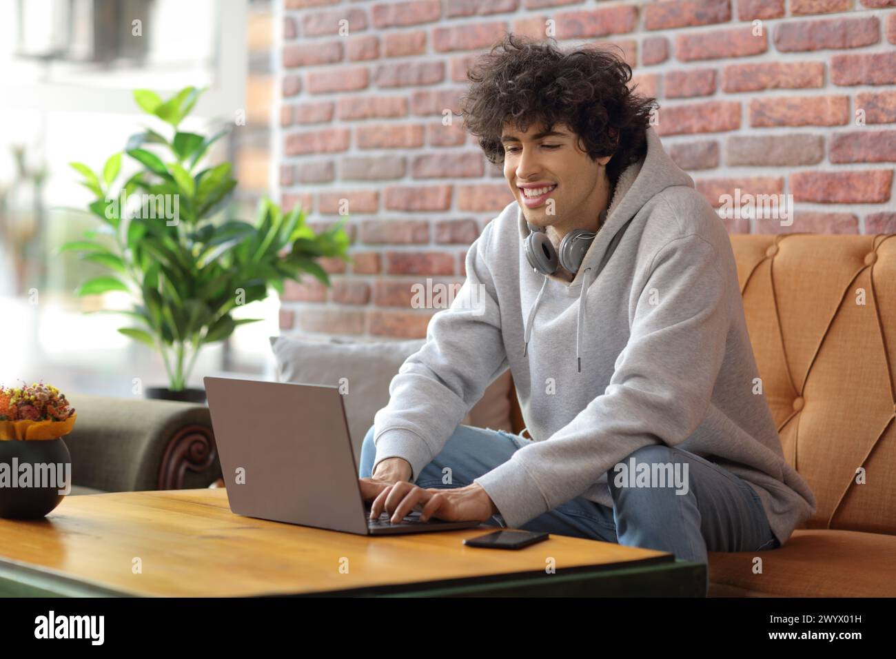 Student in a cafe sitting on a sofa and using a laptop computer Stock Photo