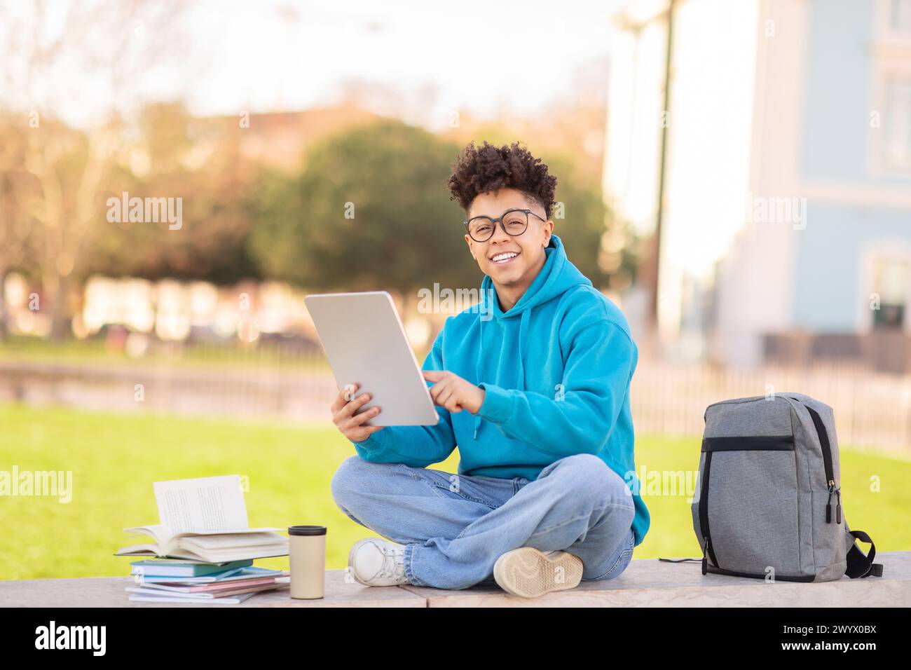 Happy student using tablet outside, studying at park Stock Photo