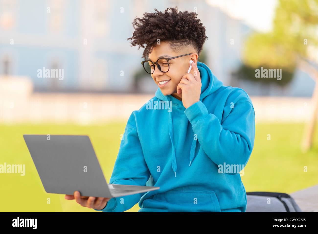 Man using phone and laptop simultaneously, studying at park Stock Photo