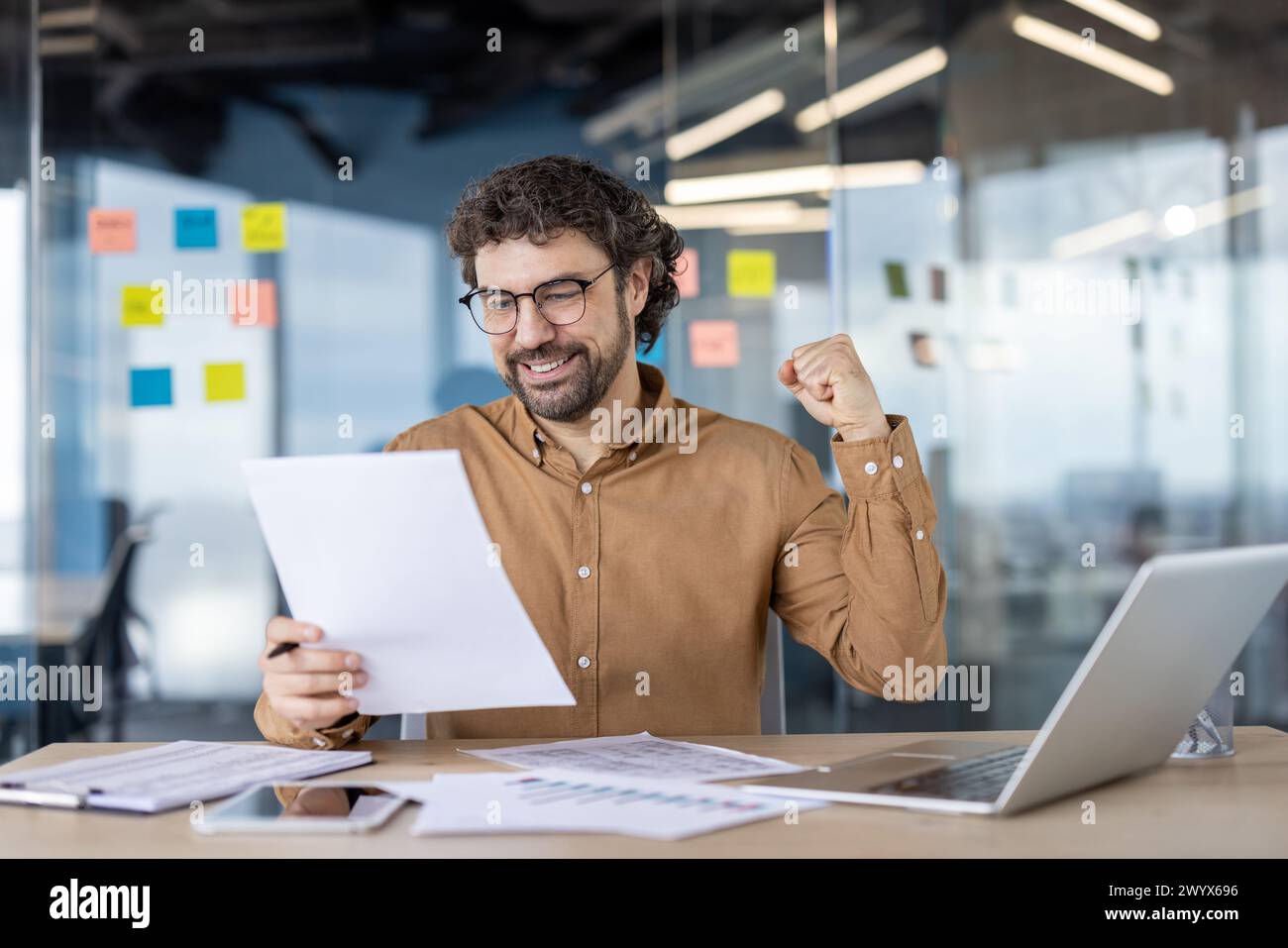 Excited male professional cheers with a fist pump while reviewing ...